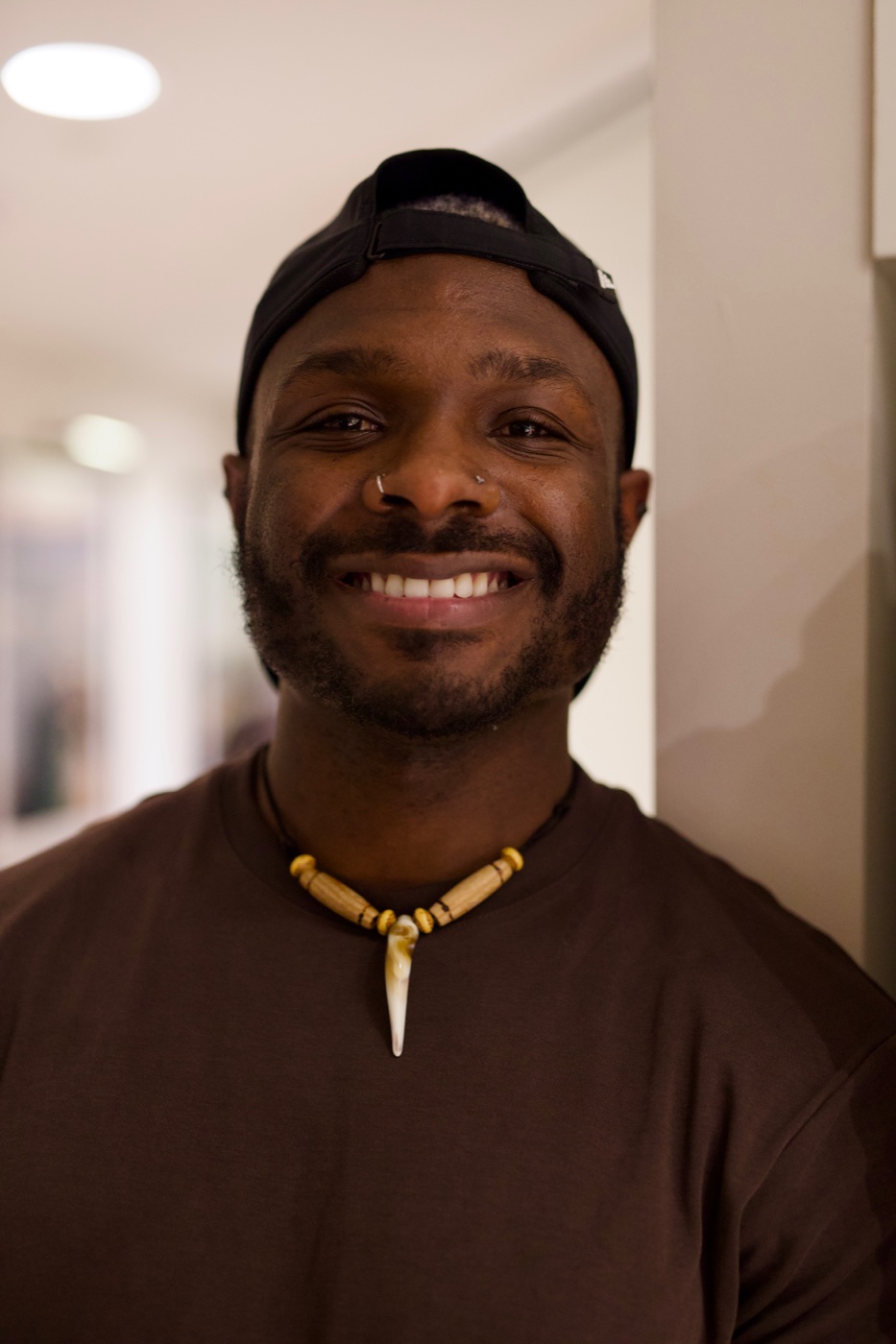 A-WIRE smiling in a black cap and brown shirt